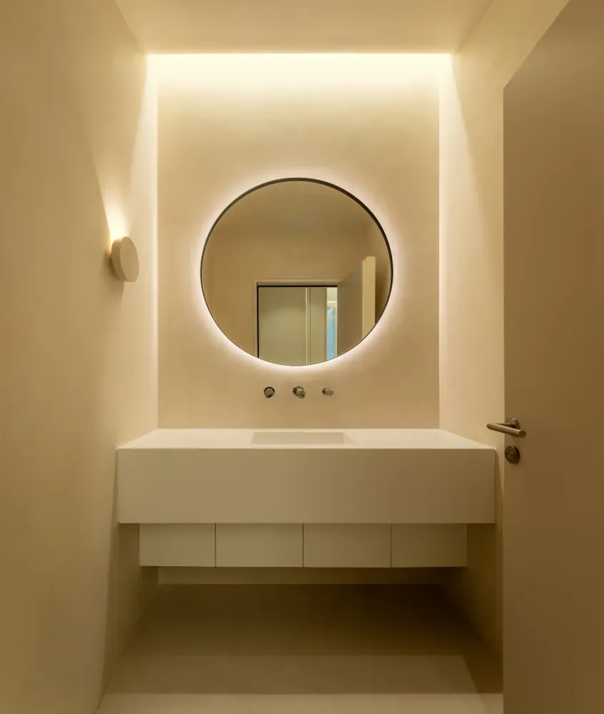 Washroom with backlit round mirror