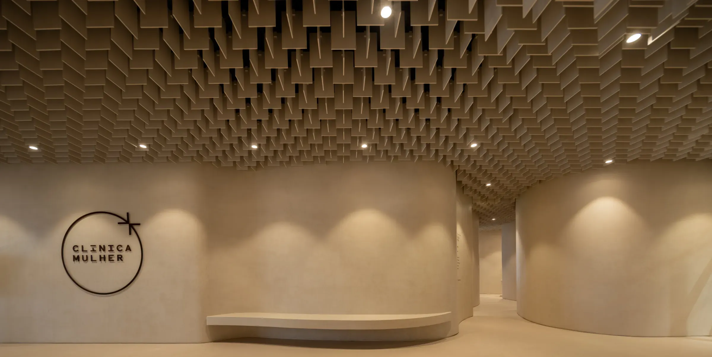 Clínica Mulher waiting area with logo wall and curved bench